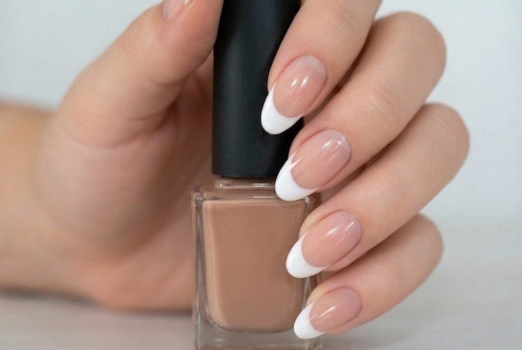 long french tip nails holding nude nail polish bottle showing healthy nail growth results