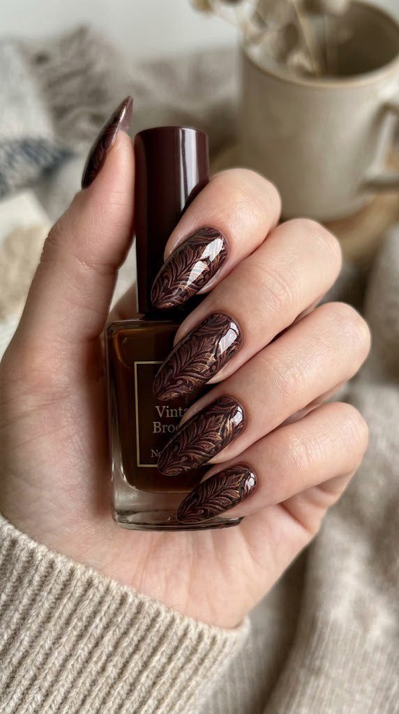 Long almond nails featuring dark burgundy and metallic bronze vintage brocade textile print
