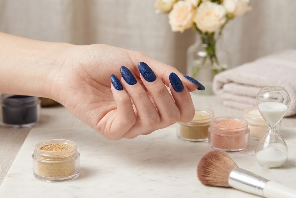 navy blue almond shaped dip powder nails with colored powder jars and hourglass