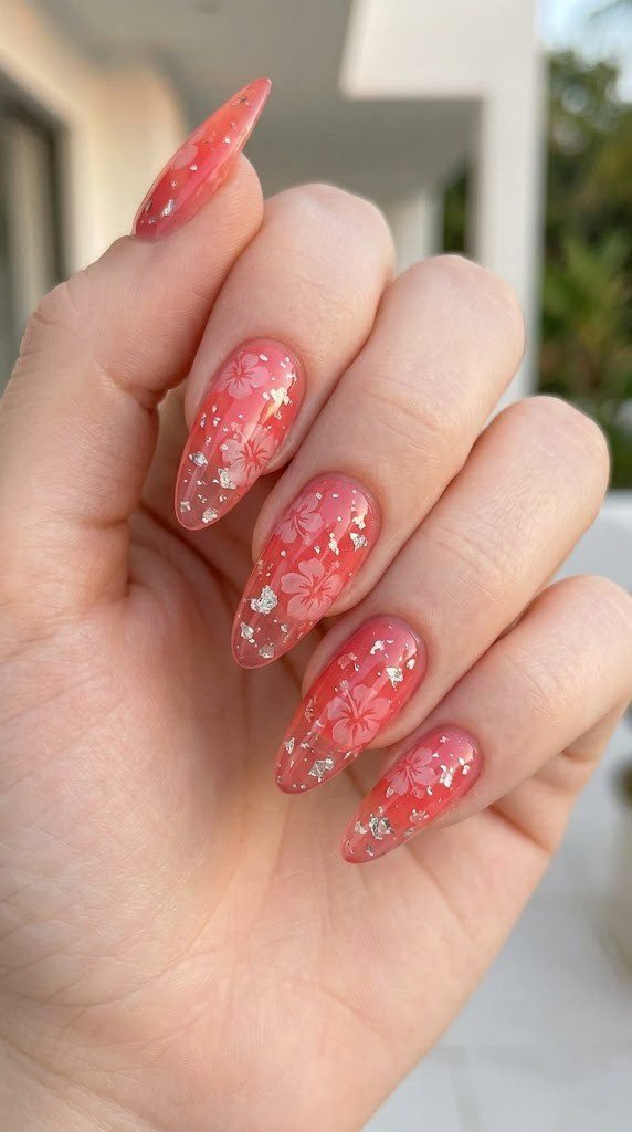 Translucent coral pink jelly almond nails with hibiscus motifs silver foil and fine glitter shimmer