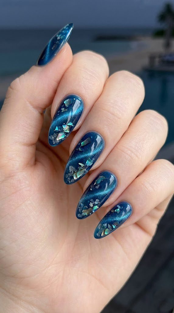 Deep teal blue cat-eye magnetic almond nails with abalone shell and iridescent crushed sea glass
