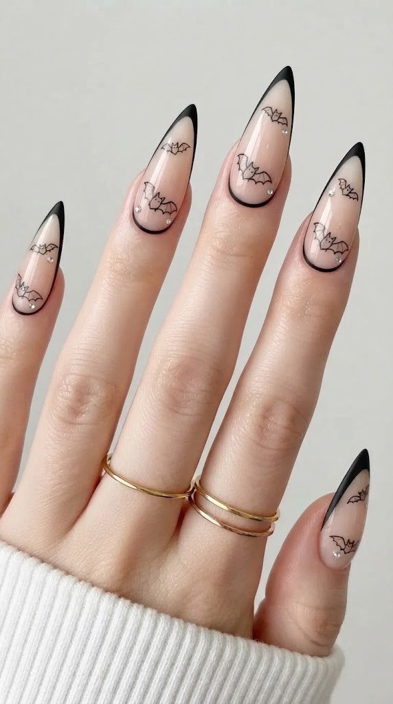 Nude stiletto Halloween French tip nails with a crystal bat traced in black
