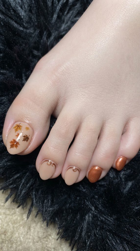 almond toe nails with maple leaves and brown chrome swirl design