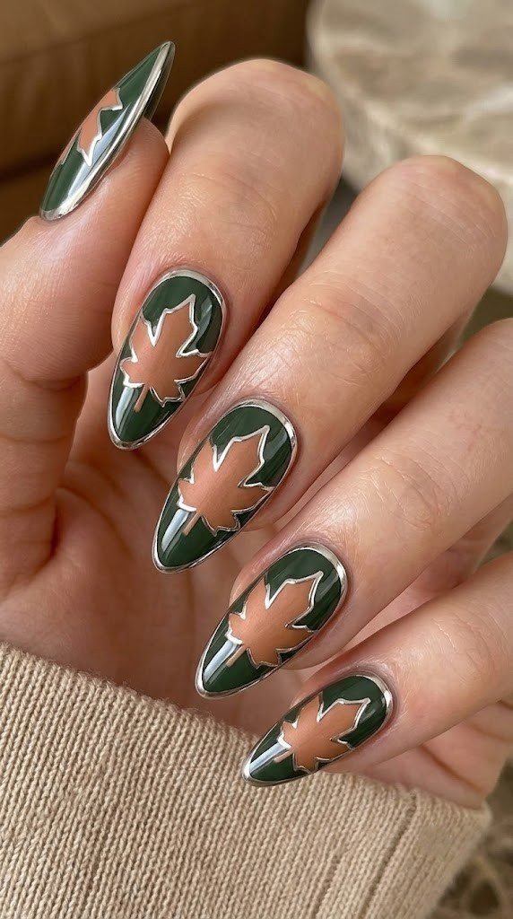 Moss green almond nails with a copper maple leaf framed in platinum chrome