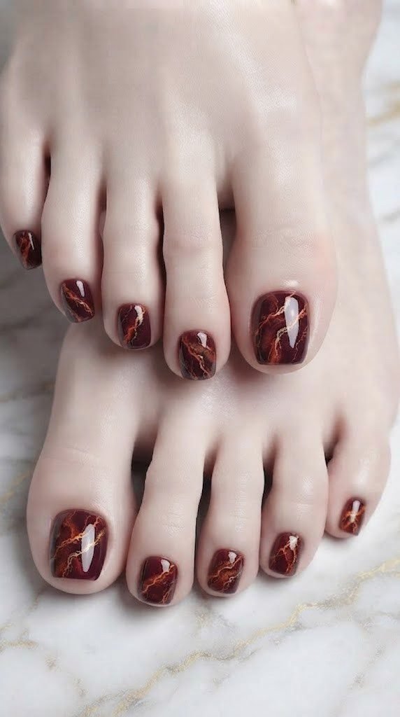 Onyx stone vein toe nail design in burgundy with orange and gold