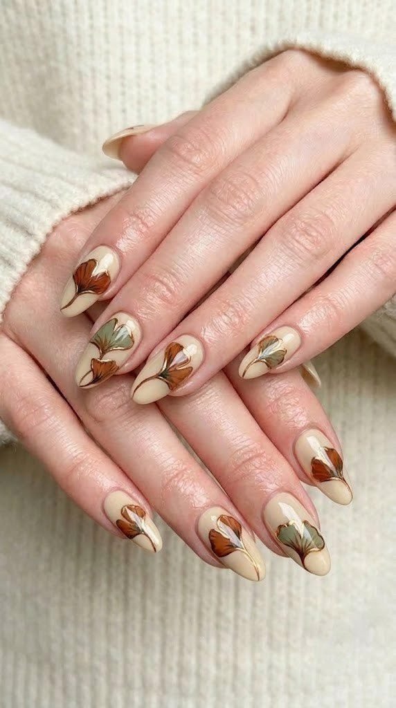 Creamy oatmeal almond nails with ginkgo leaves outlined in bronze chrome