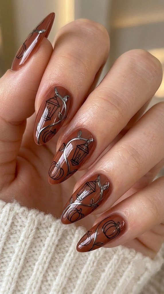 Burnt terracotta almond nails with pumpkin lanterns traced in gunmetal chrome