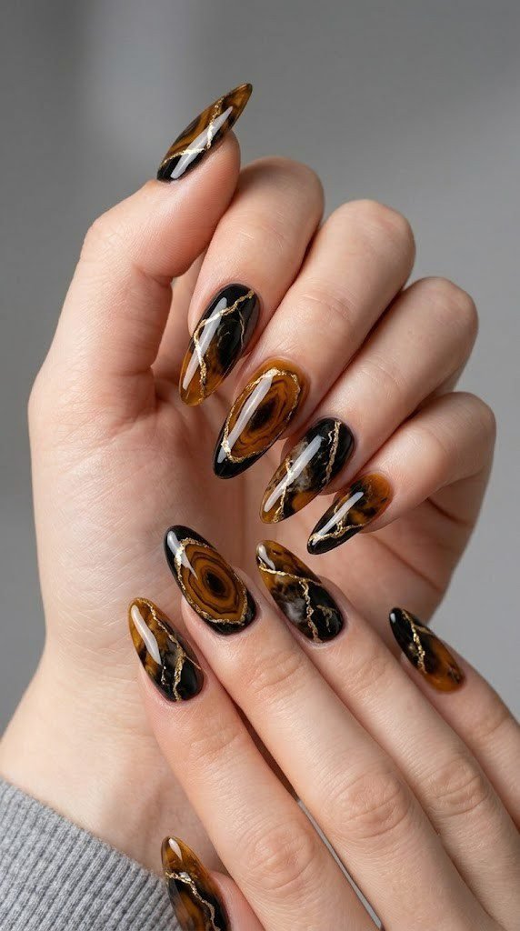 Translucent amber and obsidian black geode nail design with metallic gold vein detailing