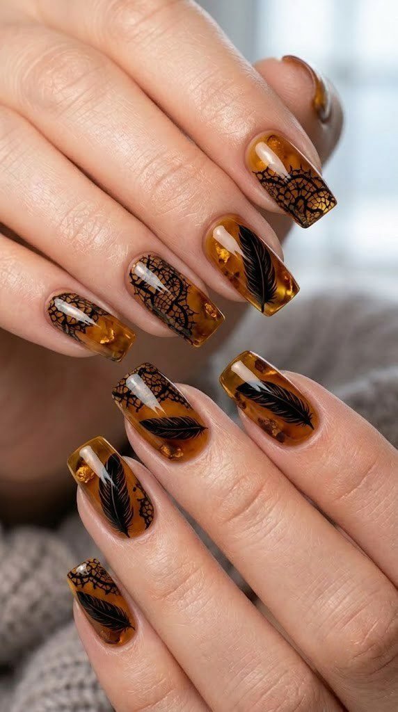 Translucent amber nails with glossy raven feather illustrations and shattered black lace