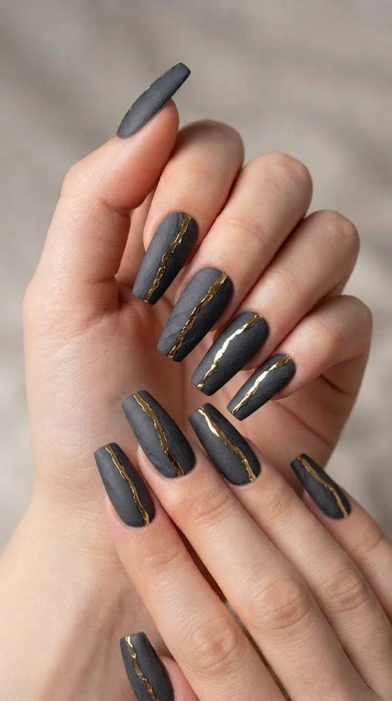 Matte charcoal fall nail design split by a reflective gold foil vein