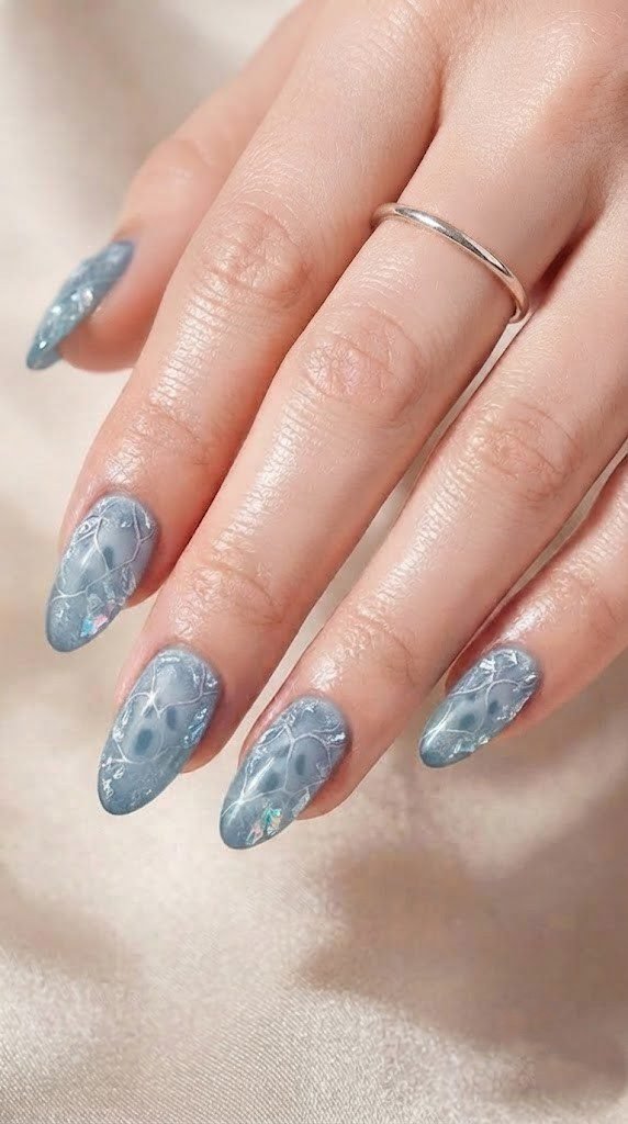 Matte black nails with a silver scythe and scattered tiny skulls design