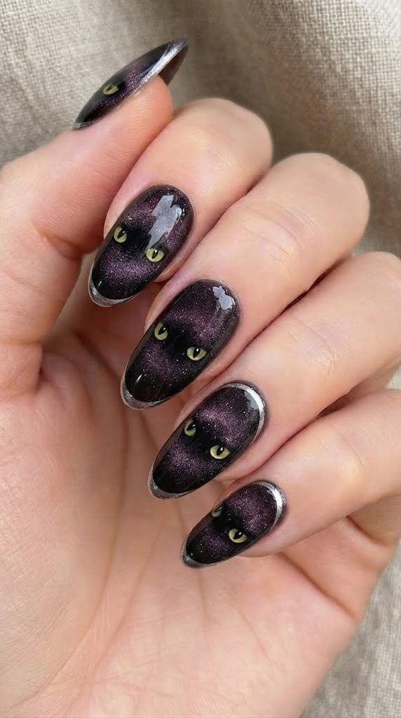 Plum cat-eye nails with glowing yellow cat silhouettes, a witchy spooky nails look