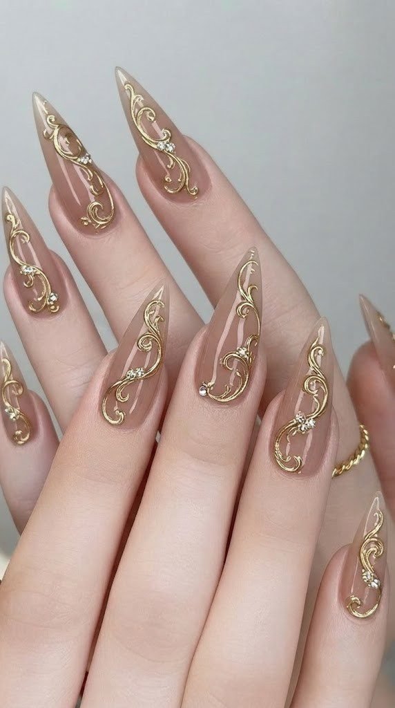 Stiletto fall nail design with mocha nude base and sculptural gold filigree